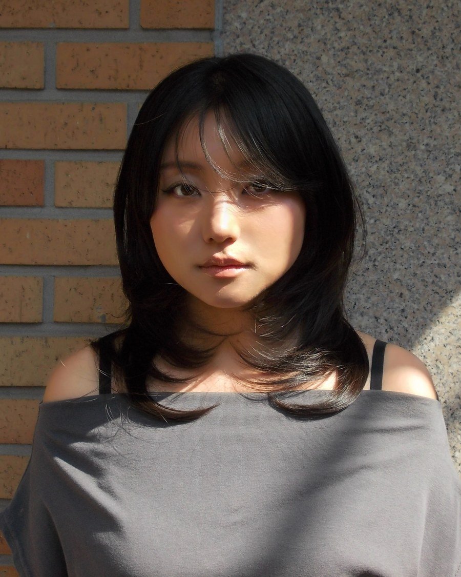 Smiling East Asian woman outdoors with shoulder-length dark hair in soft bouncy layers