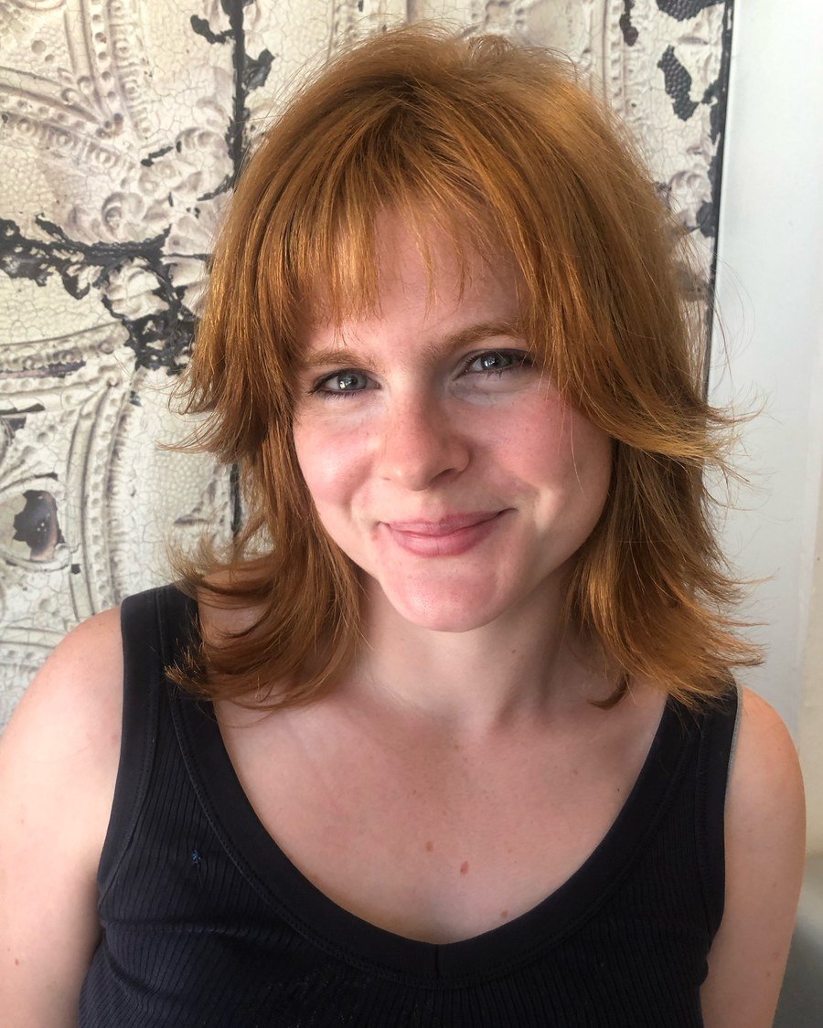 Woman with shoulder-length reddish-orange wolf cut, choppy layers and wispy bangs