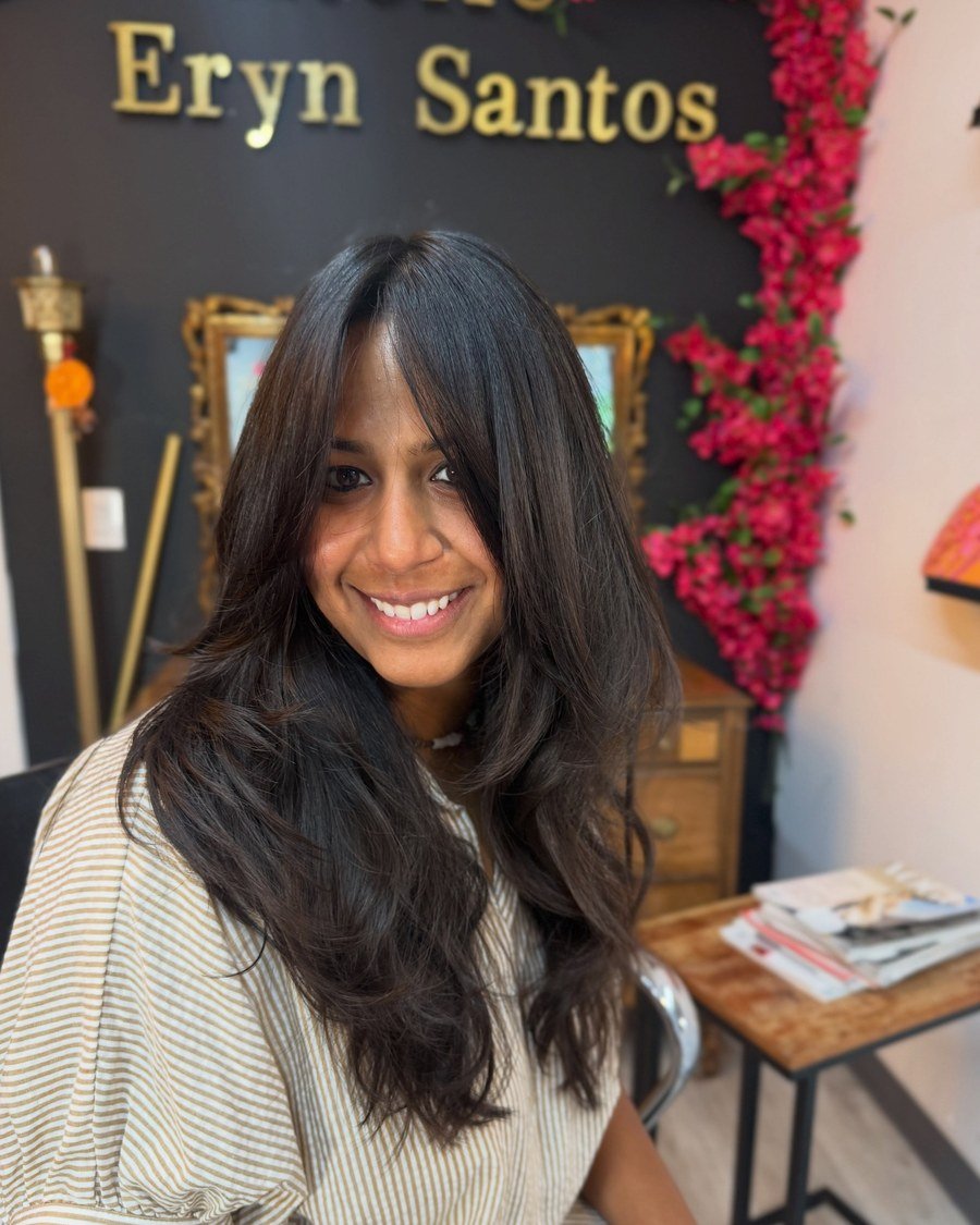 Smiling young woman with dark brown wavy butterfly cut and face-framing layers