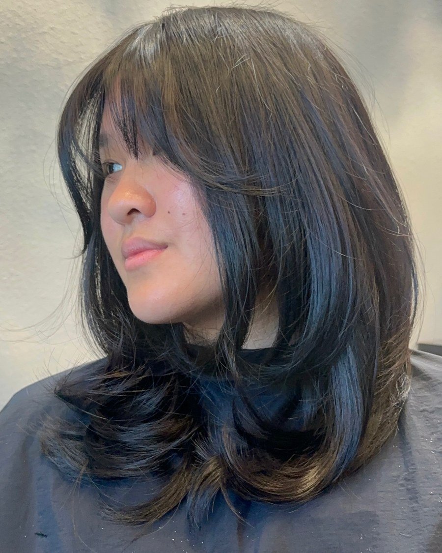 Side profile of dark brown shoulder-length hair with wispy narrow bottleneck-style bangs