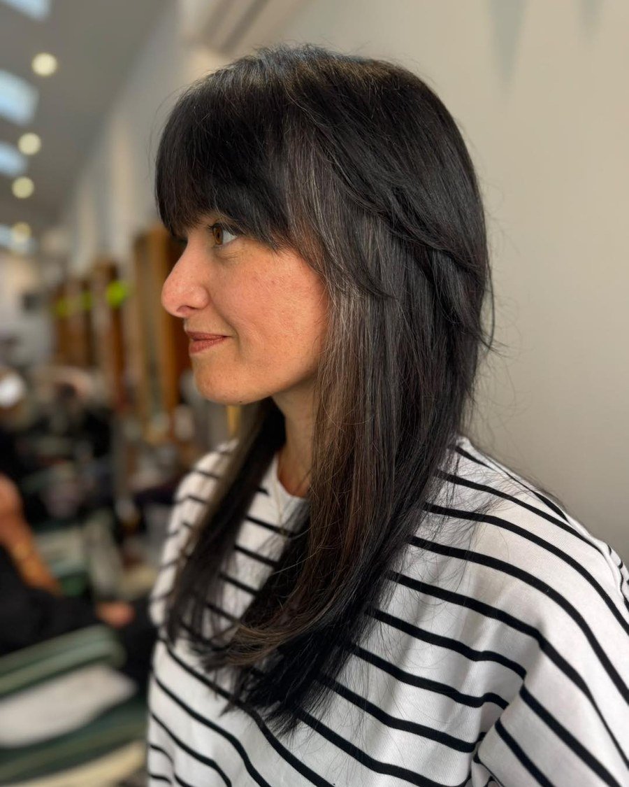 Side profile of shoulder-length dark hair with lighter feathered layers framing the face