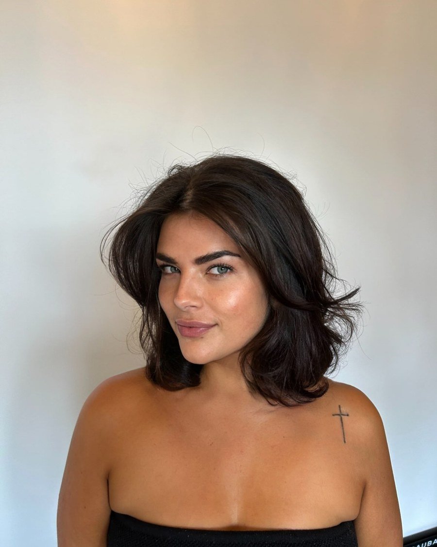 Young woman with dark shoulder-length wavy hair in a voluminous blowout