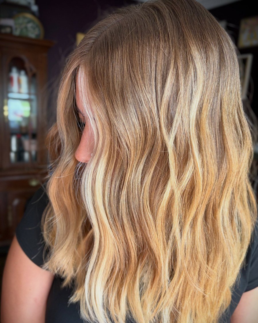 Side-back view of shoulder-length softly waved warm golden-blonde balayage