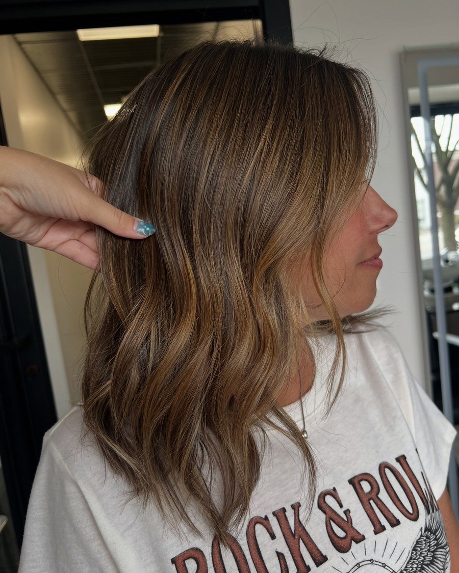 Side profile of shoulder-length wavy hair, rich brown base with caramel balayage