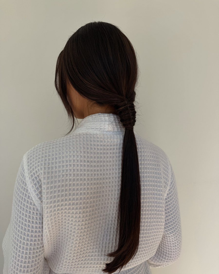 Rear view of sleek low ponytail with twisted wrap detail at the nape