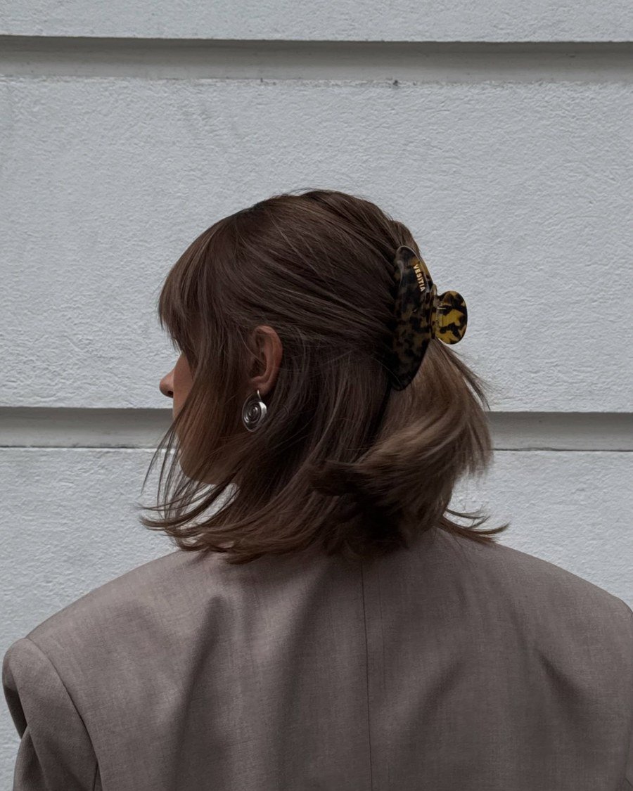Shoulder-length dark brown hair with bangs styled with a large tortoiseshell claw clip