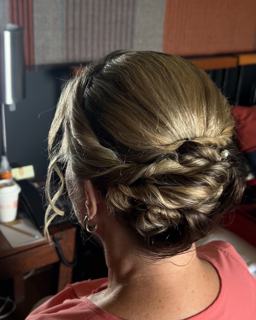 Rear close-up of shoulder-length highlighted hair in a low braided bun with soft curled strands